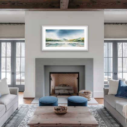 Watercolor painting of Lochranza at dawn in a living room setting with neutral coloured furnishings . A dark, dramatic blue sky hangs over rolling green and ochre hills. A calm, light-reflecting body of water sits in the center, with small white sailboat masts visible in the distance. The foreground shows the textured, shallow edges of the shoreline in muted blues and greys.